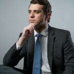 Businessman in suit poses thoughtfully against a neutral background, embodying professionalism.